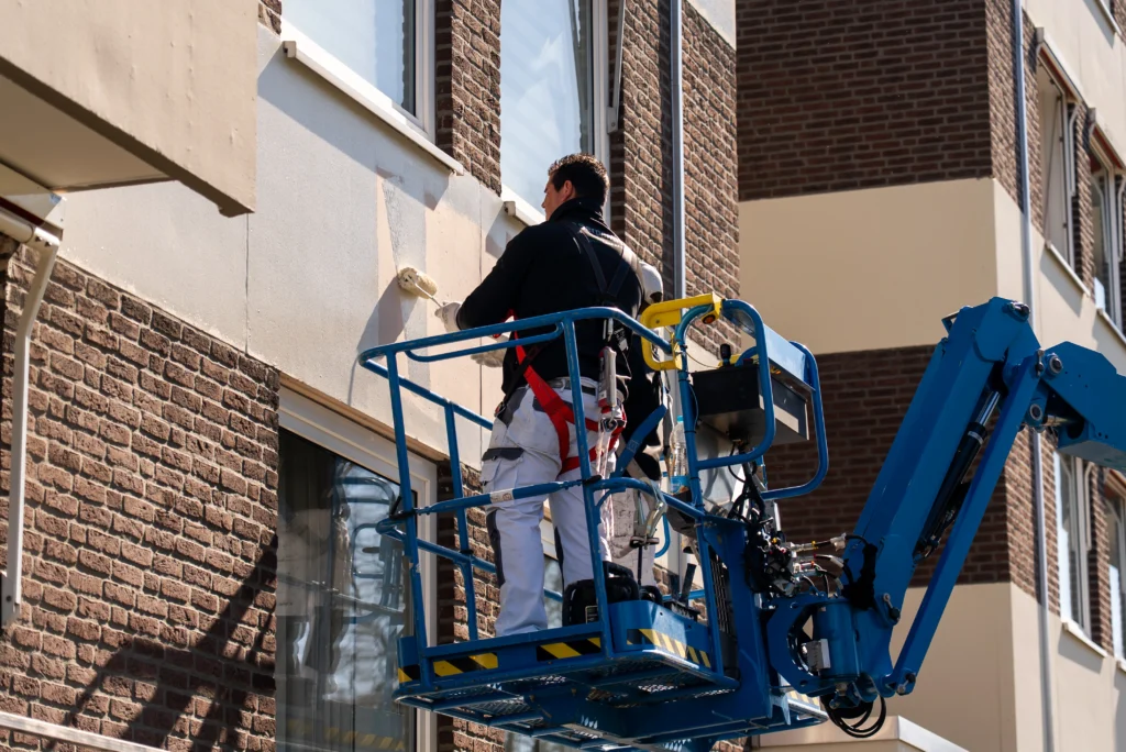 Schilder op hoogwerker bij renovatie van appartementencomplex