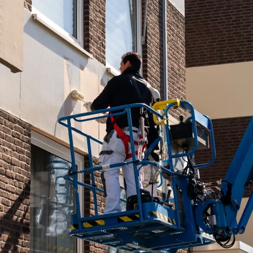 Schilder op hoogwerker bij renovatie van appartementencomplex